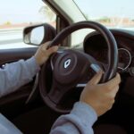 Close-up of hands on steering wheel while driving through Mexico in daylight.