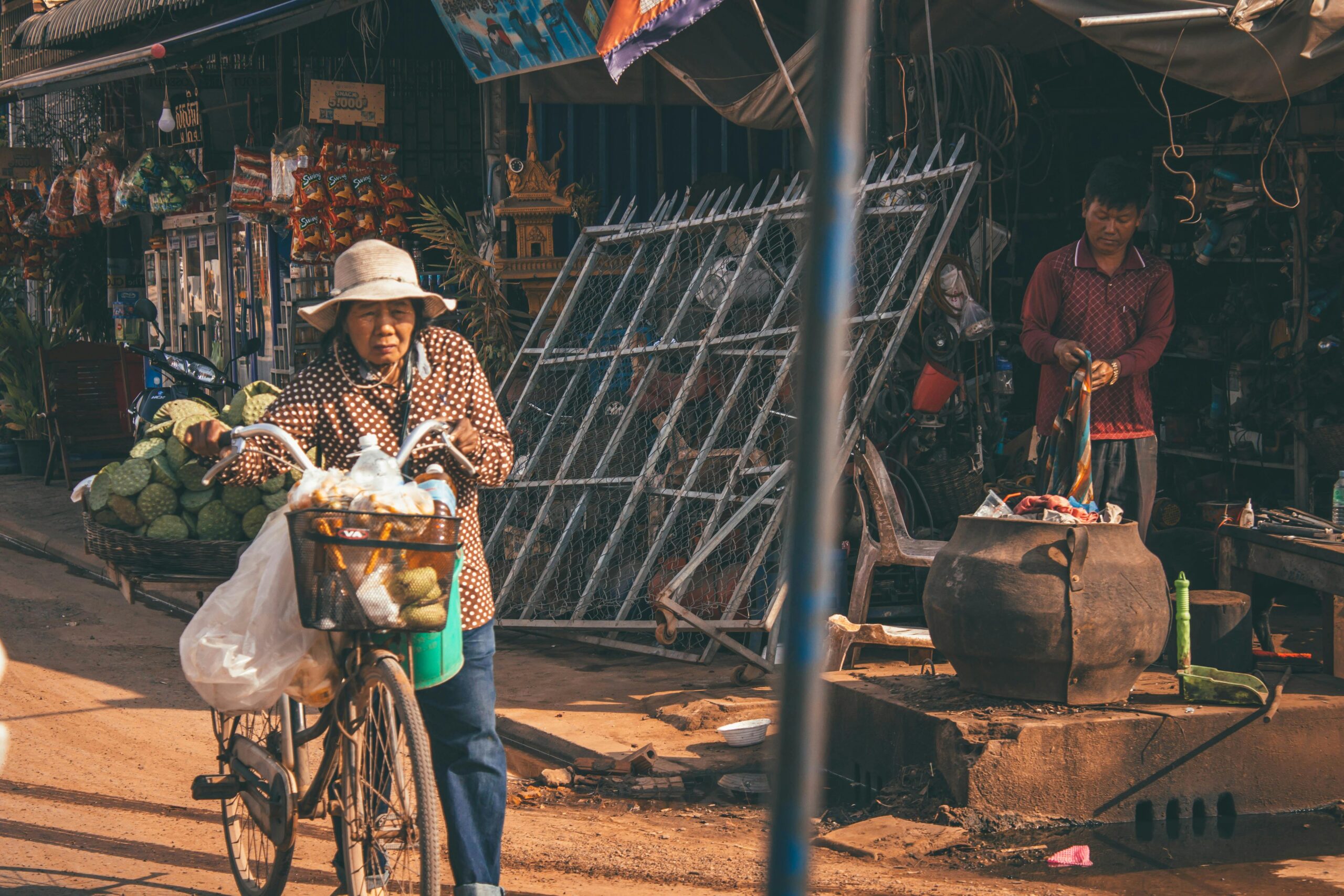 Elderly woman selling fruits on a bicycle in Siem Reap market street, Cambodia.