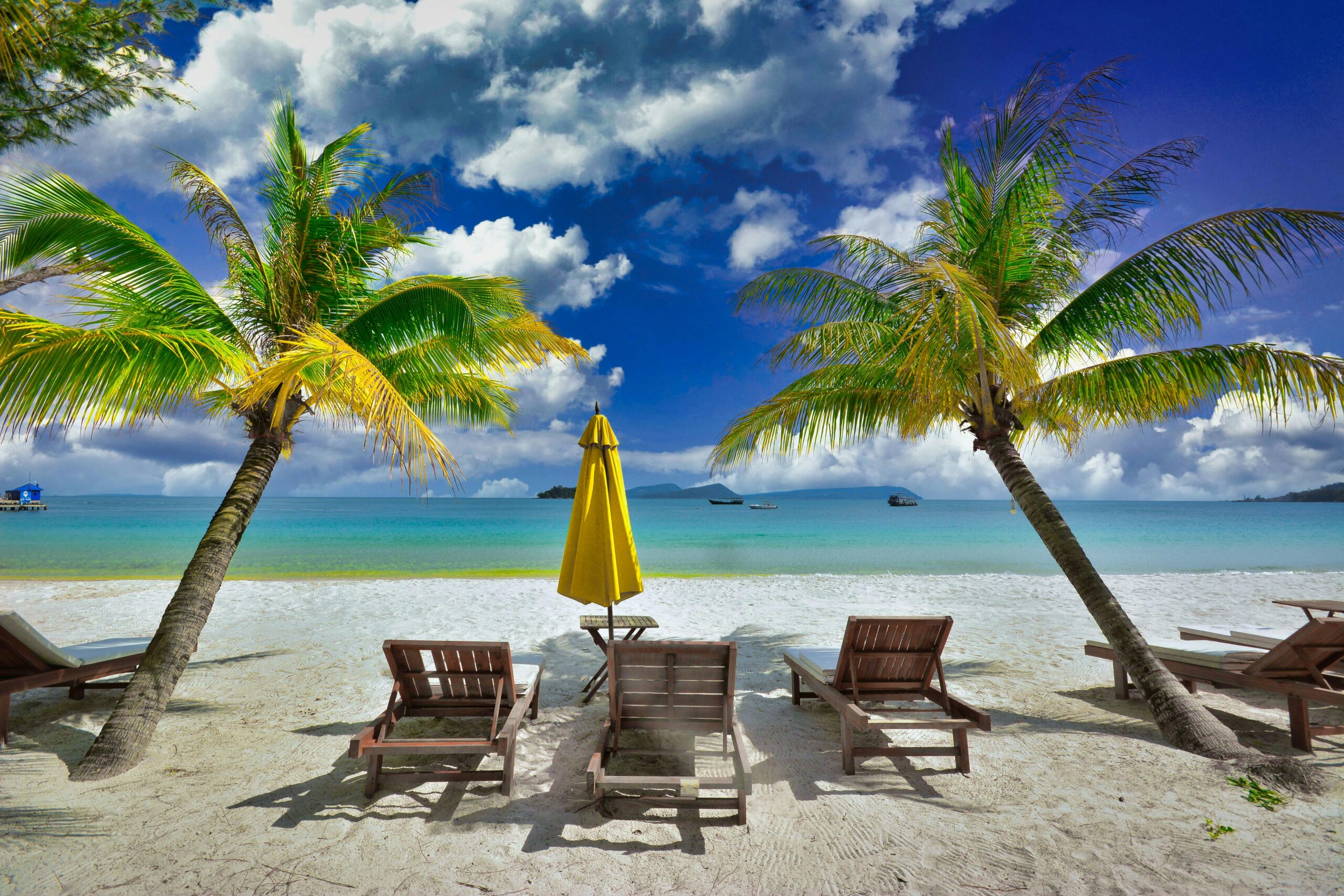 Peaceful tropical beach with palm trees and lounge chairs in Koh Rong, Cambodia.